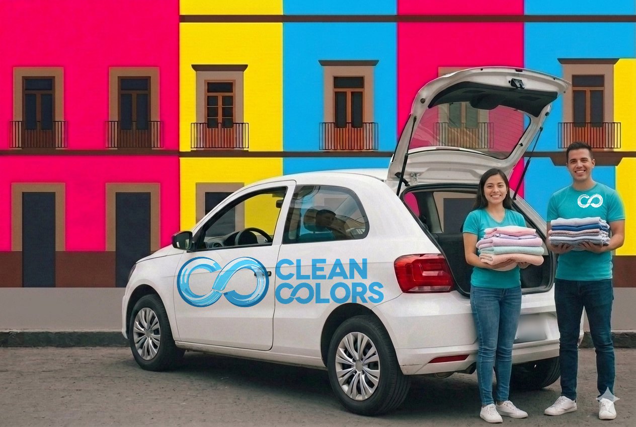 Una mujer y un hombre con playera turquesa de Clean Colors suben ropa limpia y doblada a la cajuela de un coche rotulado, frente a fachadas de colores